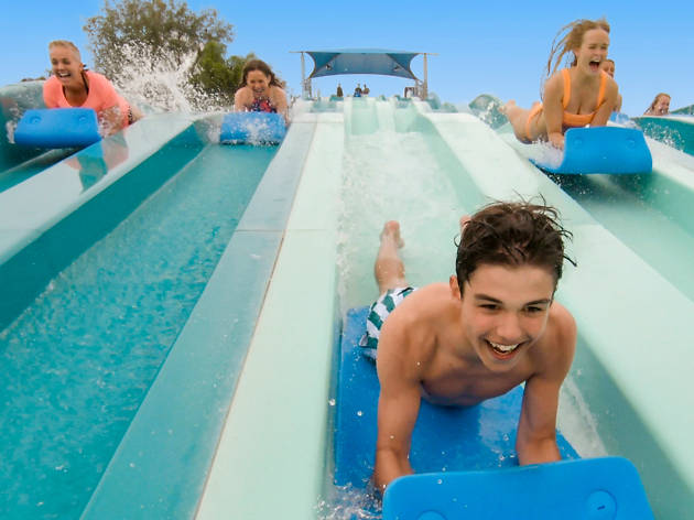 Aqua Racer at Adventure Park Three people racing down a waterslide on foam mats