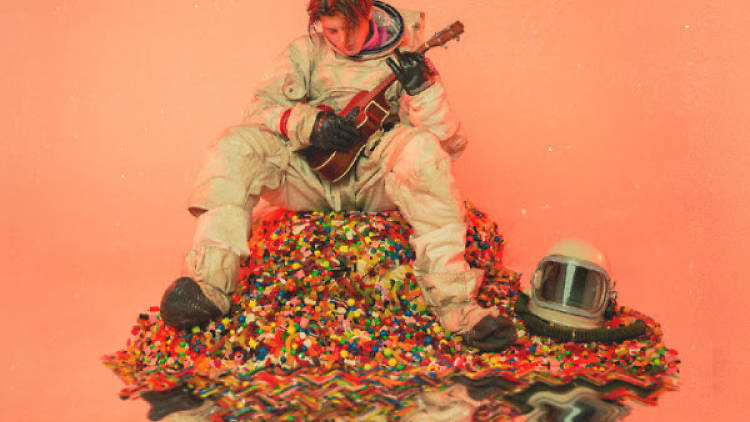 Ruel pictured in a spacesuit with a guitar on a pile of lollies