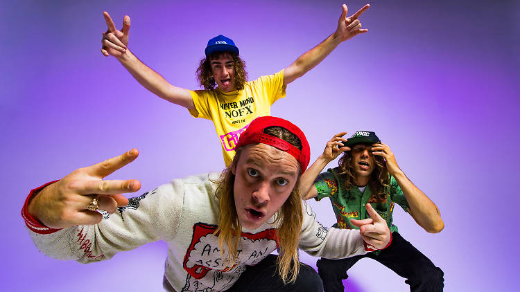 Dune Rats posing for a band photo on a purple background.