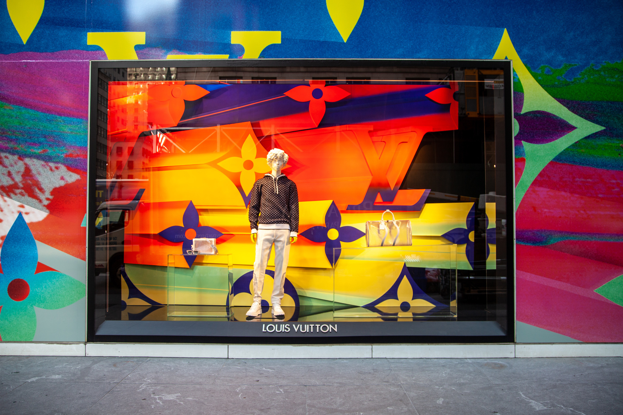 A reflection in Bergdorf Goodman window of the newly opened (curbsidee  pickup only) Louis Vuitton 5th Ave. flagship store, decorated with a large  rainbow in honor of “Pride Month”, New York, NY