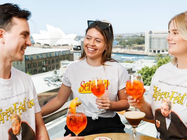 Festivus The Glenmore Three people wearing Seinfeld and Festivus themed shirts drink Aperol Spritz.