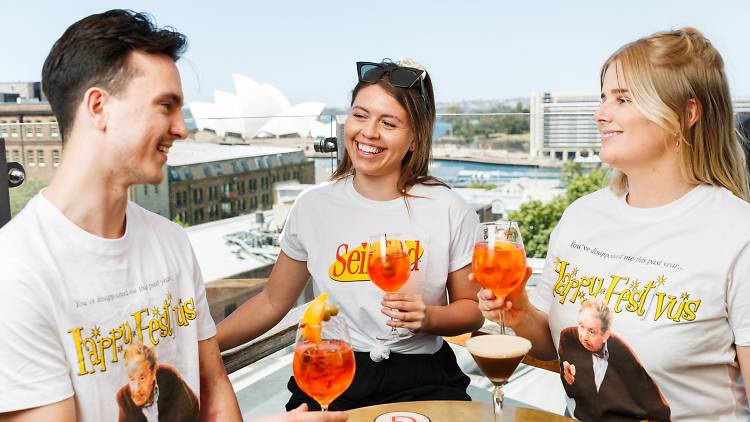 Three people wearing Seinfeld and Festivus themed shirts drink Aperol Spritz.