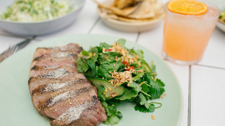 A plate of sliced meat with salad and an orange cocktail.