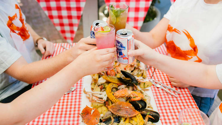 People toasting their drinks over a long plate of seafood