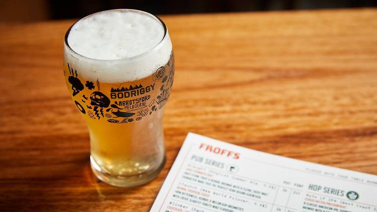 A glass of beer with Bodriggy Brewing motifs next to a beer list. 