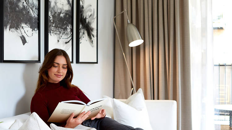 White living room with a woman reading her book