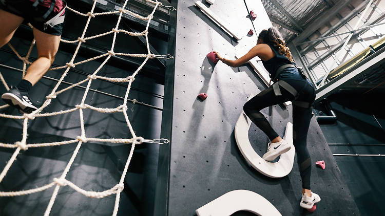 Woman climbing up an indoor rock climbing wall