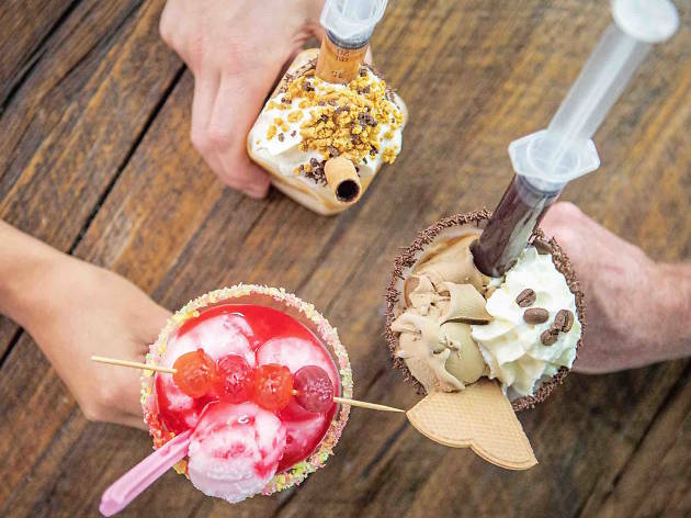 Ice Cream Fest at Ascot Lot Top down photo of three hands holding different, elaborate sundaes