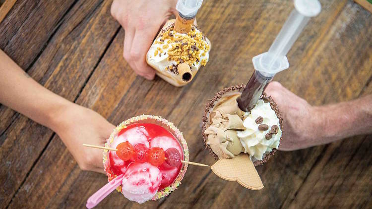 Top down photo of three hands holding different, elaborate sundaes