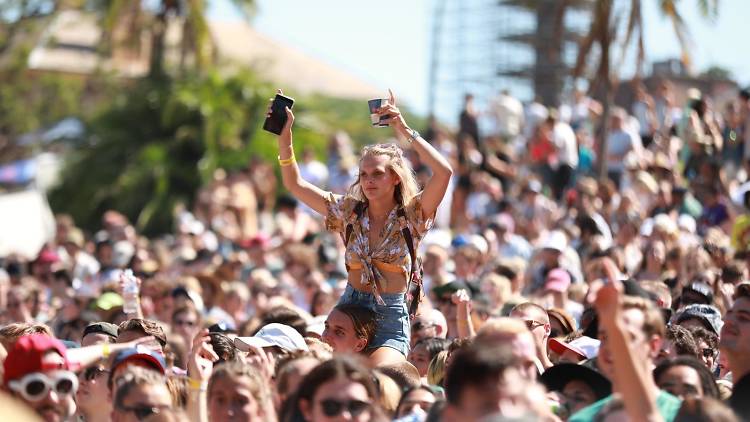 A crowd gathered at Laneway festival, a young woman rides on someone's shoulder. 