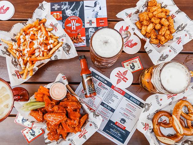 Winghaus by Bavarian A table with buffalo wings, potato gems, chips, pretzels and beer