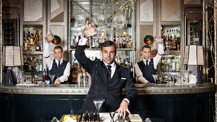 Three bartenders pouring Martinis from up high at the Connaught Bar