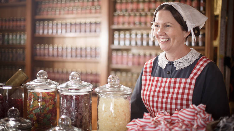 A woman in an 1850s outfit behind the counter in a sweet shop