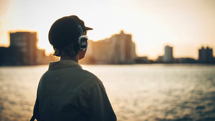 A person looking out over the water with wireless headphones on