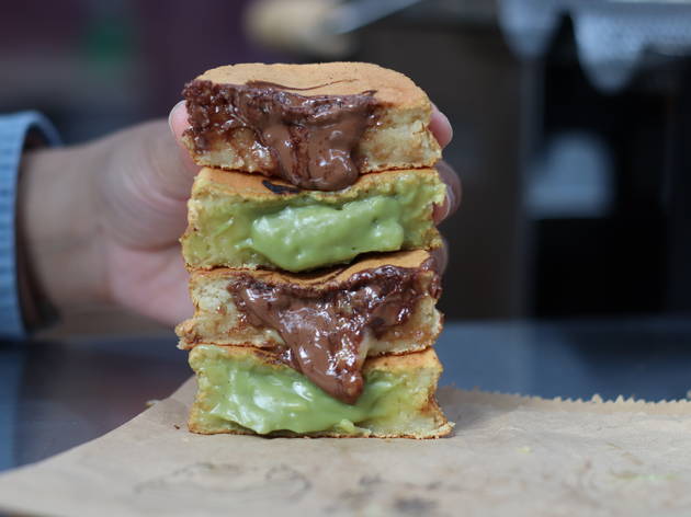 A wheelcake dessert bar has arrived in Selfridges Two wheelcakes cut in half and stacked on top of each other as someone holds them up, with the custard oozing out of them