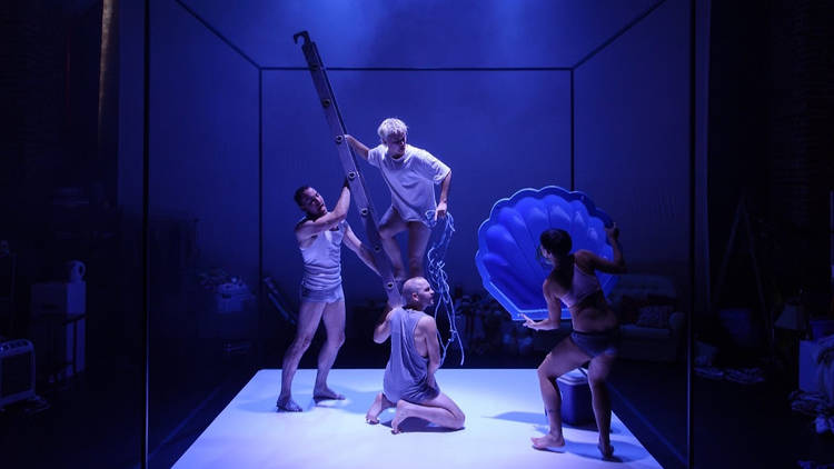 People in white dancewear performing under a blue light