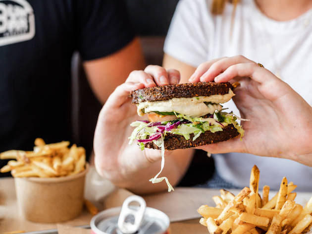 Falafel burger at BunBar Two hands holding a burger with falafel buns