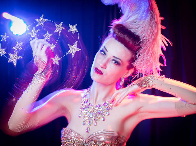 Burlesque in Sydney Porcelain Alice wears soft pink glittering outfit and accessories, she is twirling a crown of stars and staring into the camera.