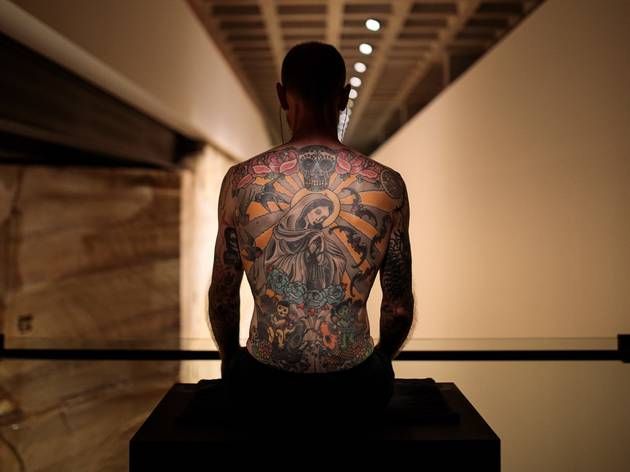 Tim Man with a tattooed back sitting on a box