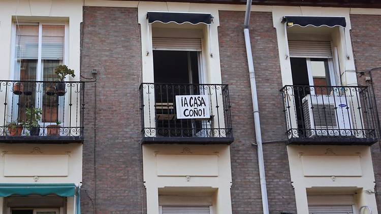 Un balcón con un cartel pidiendo que la gente se queda en casa