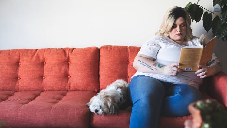 Woman sitting on a couch reading with a small dog