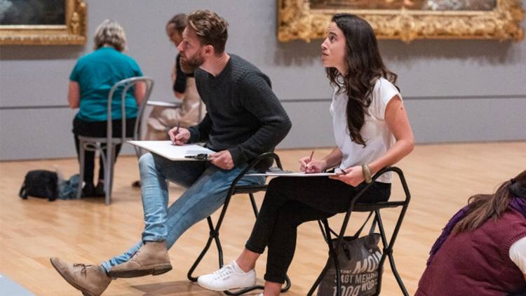 Two people sitting in a gallery drawing