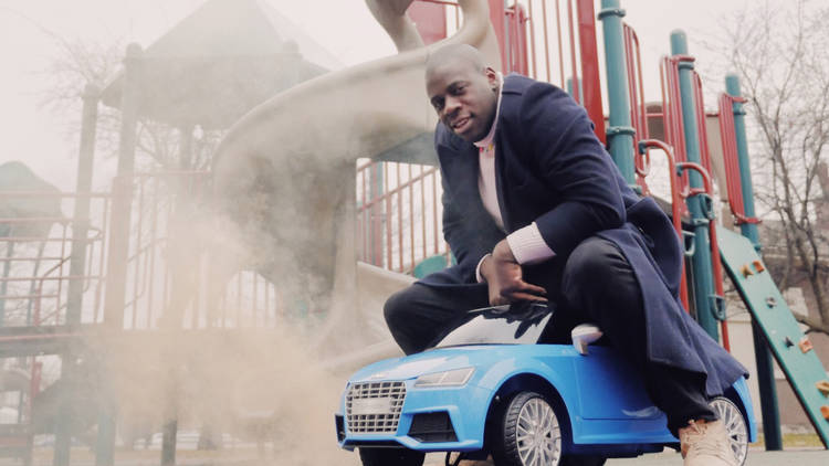 Chicago musician NNAMDI on a toy car in a park