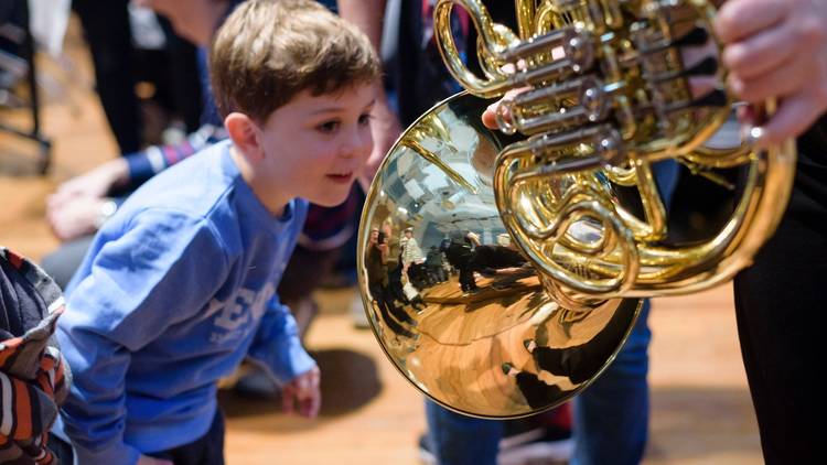 Small boy peering into a French horn