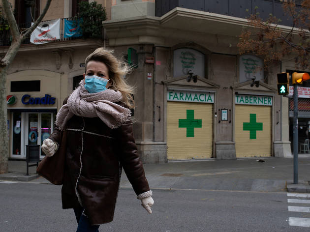 Una dona es protegeix la cara amb una mascareta Una dona es protegeix la cara amb una mascareta