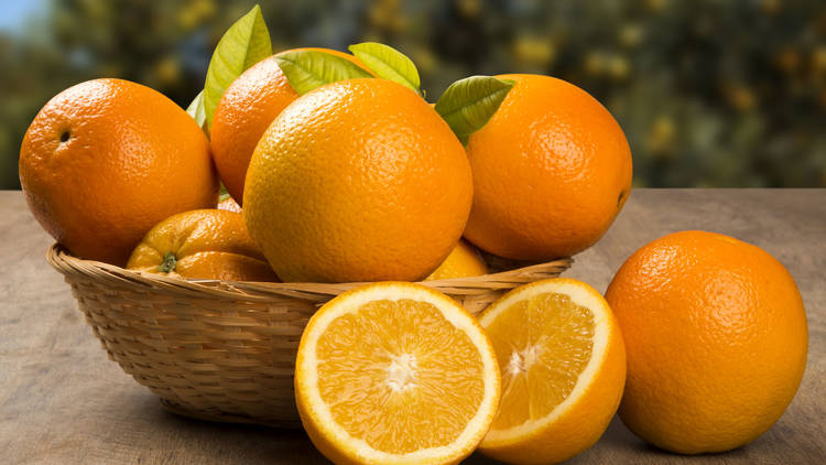 Close up of some oranges in a basket over a wooden surface