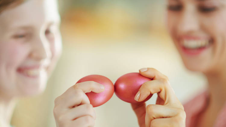 happy mother and daughter having egg tapping with easter eggs