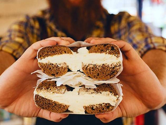 Brooklyn Boy Bagels Man holding bagel with cream cheese