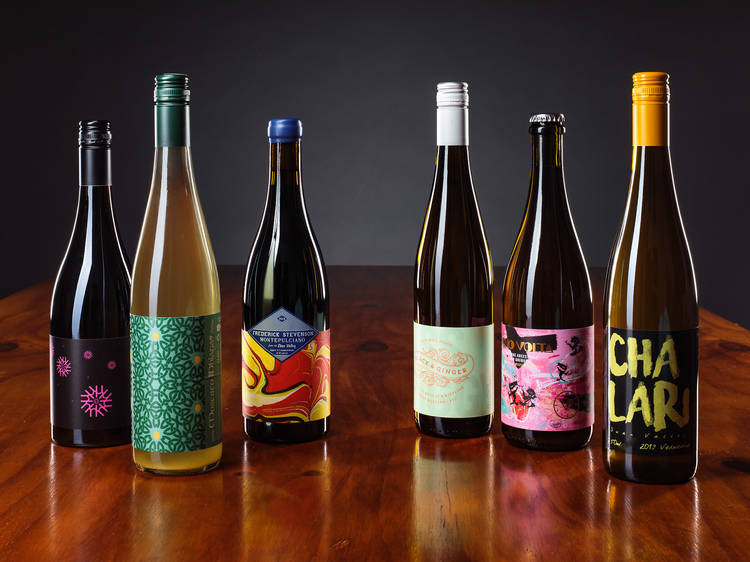 Six bottles of natural wine on a wooden table