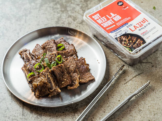 Yes, DIY Korean barbecue and fried chicken can now be delivered to you A metal plate of beef short ribs and their packaging alongside, with a pair of tongs.