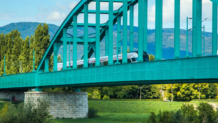 New modern fast train crossing green Railway bridge over Sava river in Zagreb 