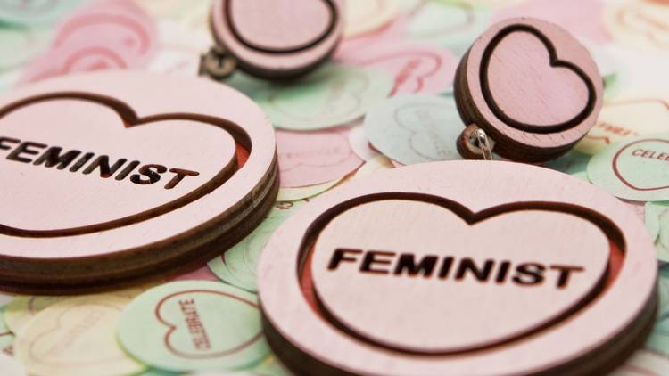 Round earrings with love hearts and 'feminist' laser cut into them