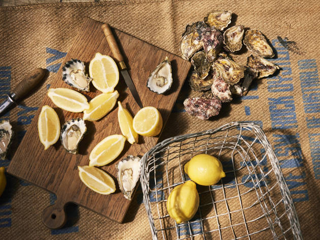 East 33 Oysters A combination of shucked and unshucked oysters on a chopping board with lemons.