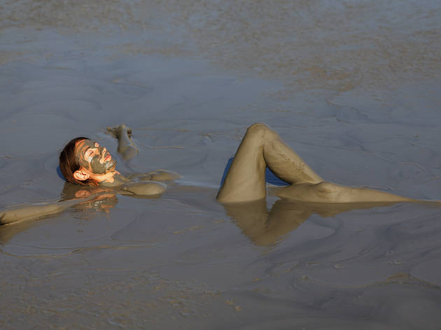 Girl takes useful procedures in the active mud volcano