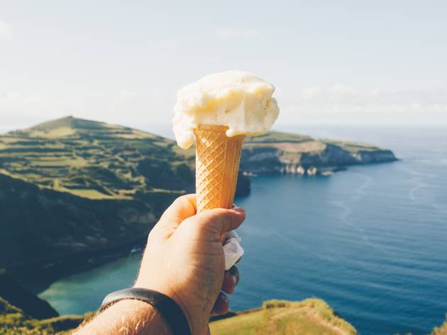 Ice cream by Sea person holding ice cream cone in front of water