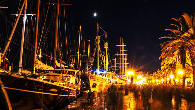 Promenade full of tourists and sailing boats in the harbor, Trog