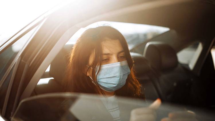 Person in back seat wearing mask