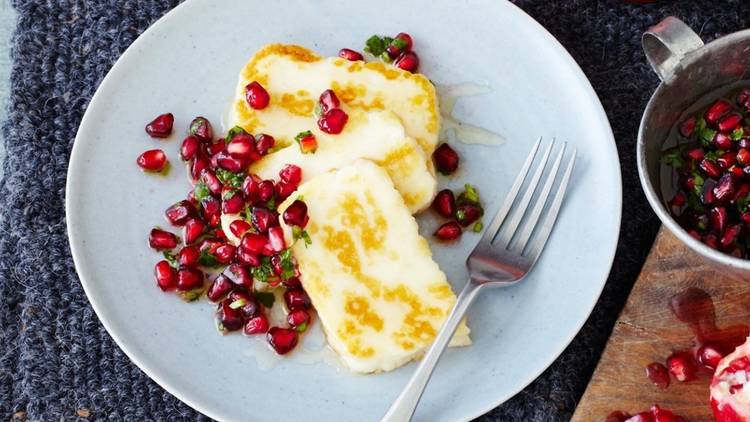 A plate of grilled halloumi slices sprinkled with pomegranite.