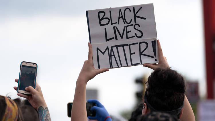 Person holding up a sign saying "Black Lives Matter!"