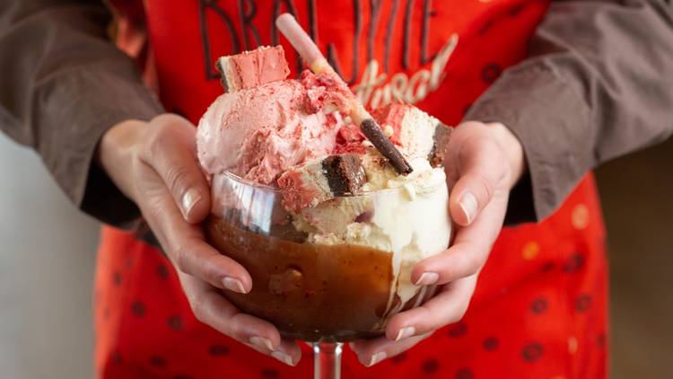 Hands holding a brownie sundae in a large glass 