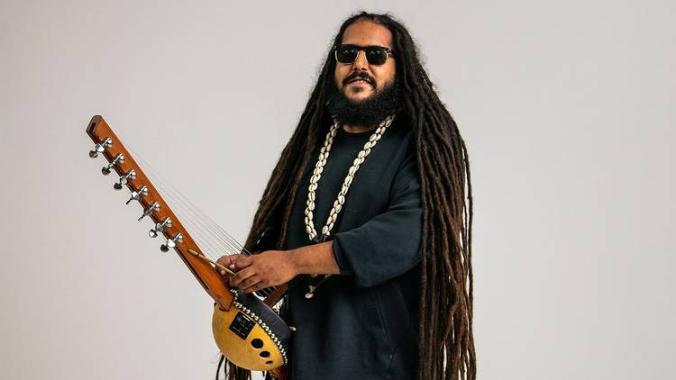 Musician and producer Julian Bel Bachir poses with traditional instrument, he has long dreadlocks
