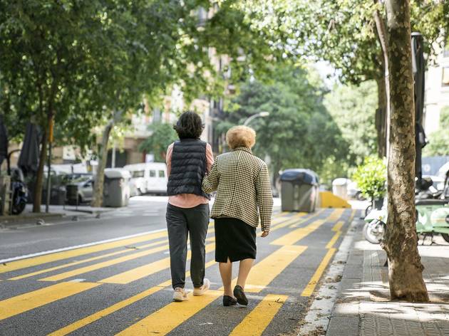Una dona gran passeja de bracet d'una altra dona per un dels nous espais ampliats per a vianants i bicicletes Una dona gran passeja de bracet d'una altra dona per un dels nous espais ampliats per a vianants i bicicletes