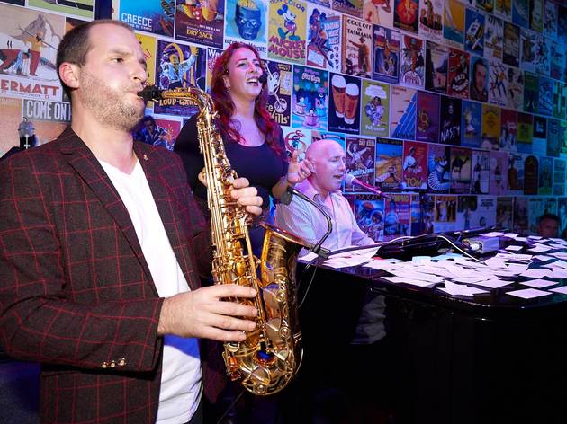 Piano Bar Geelong A saxophonist, singer and pianist performing under coloured stage lights