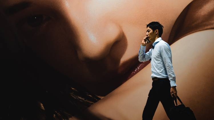Man walking in front of mural on phone