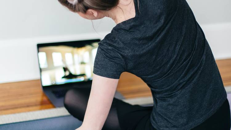 Woman stretches in front of laptop