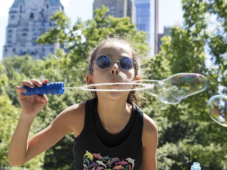 Cute girl playing with Bubbles on Central Park